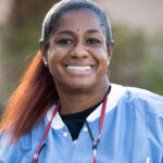Here's a short alt tag for the image: Smiling dental professional headshot.